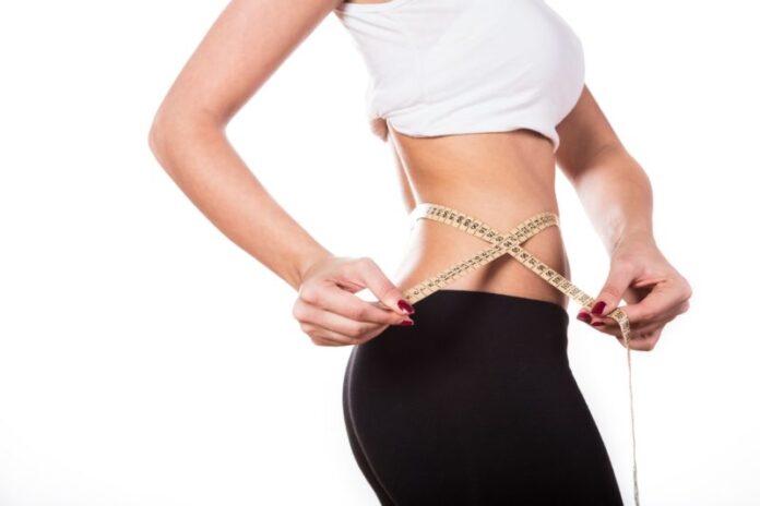 Girl measure waist to show lose weight on isolated white background, healthcare concept