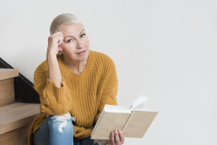 mature-woman-posing-stairs-while-holding-book-696x465